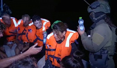 An Israeli solider passes water to those onboard the Gaza-bound British-flagged yacht